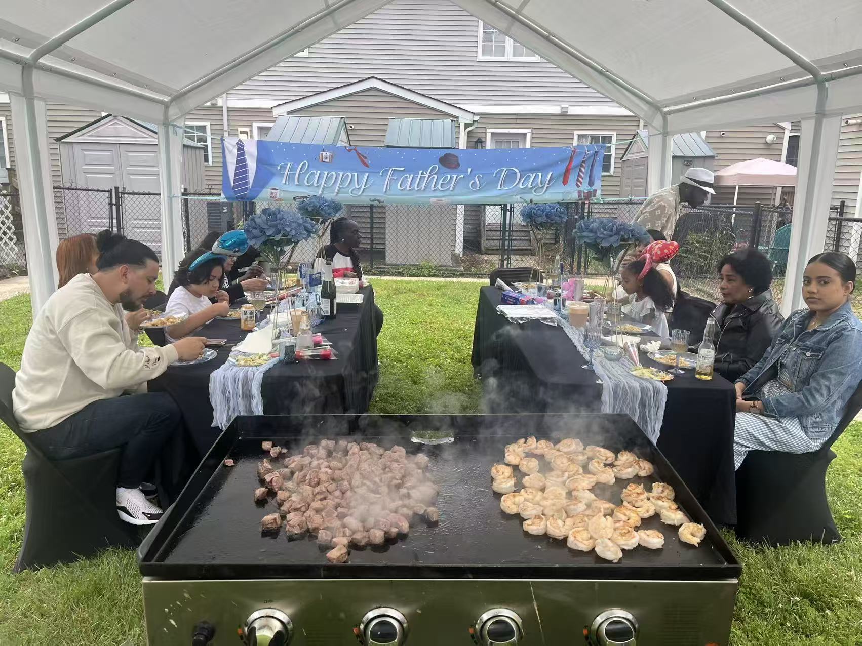 Father's Day hibachi celebration with steak and shrimp cooking on the grill under a tent