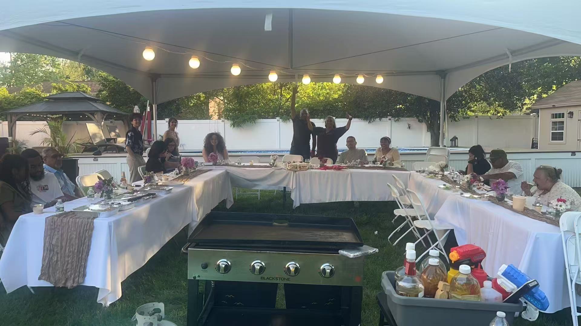 Elegant outdoor tent party with string lights and hibachi setup